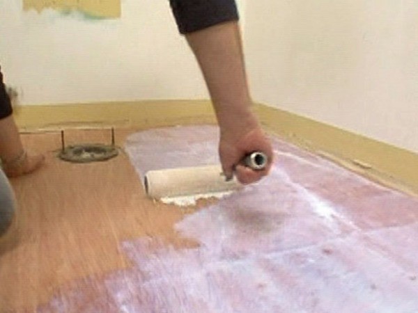 In the photo - the process of priming a wooden floor under linoleum