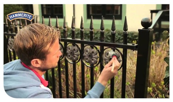 Painting a forged fence with a brush