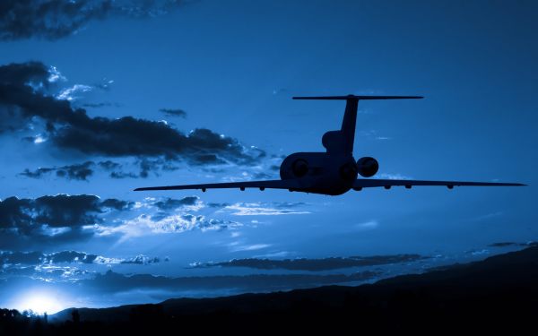 In the photo, a flying plane against the backdrop of sunrise