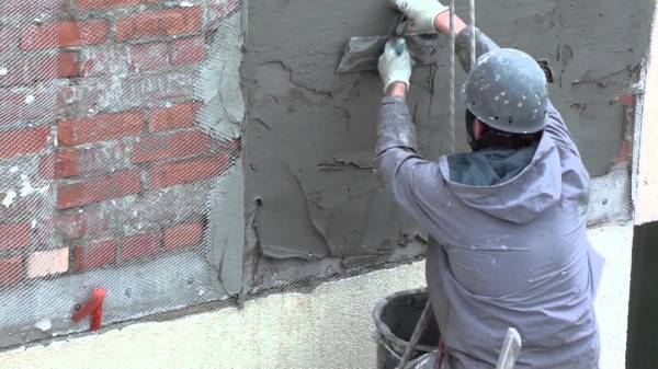 Plastering a rough brick wall with sand concrete