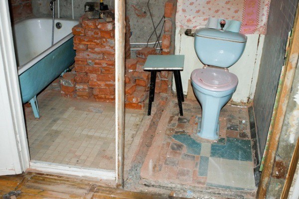 A bathroom after the demolition of a brick wall.