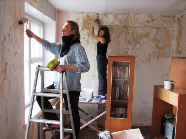 The photo shows the process of cleaning the walls and applying a special protective composition of the house with your own hands