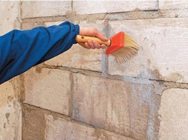 The photo shows the process of preparing brick walls with a special composition, before gluing them with plasterboard sheets