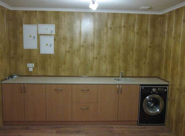 The photo shows an example of decorating the walls of the kitchen with MDF panels, which looks aesthetically pleasing and quite noble, resembling wood trim, but much cheaper