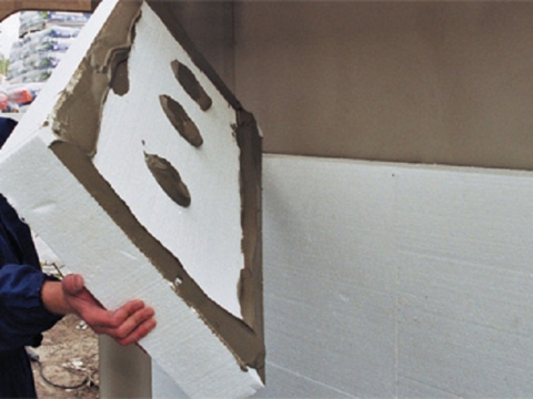 Styrofoam can be glued to concrete or brick walls using a cementitious compound.