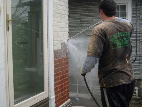 In the photo we see how the paint is applied to the brick wall of the house with a spray gun, but not all types of paints can be sprayed