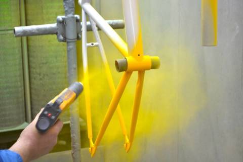 Spraying polymer powder onto a bicycle frame.