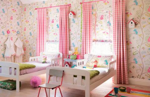 The symmetrical arrangement of beds and curtains on the windows balance the free wallpaper pattern